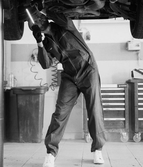 Man technician in professional attire standing confidently in repair workshop